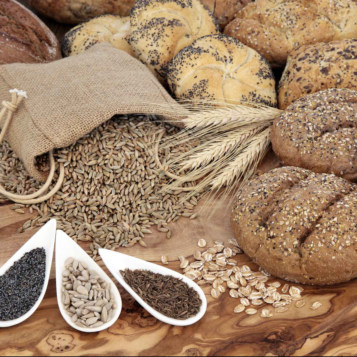A close-up shot of caraway seeds, on the table, spilling out of a bag, and on bread.