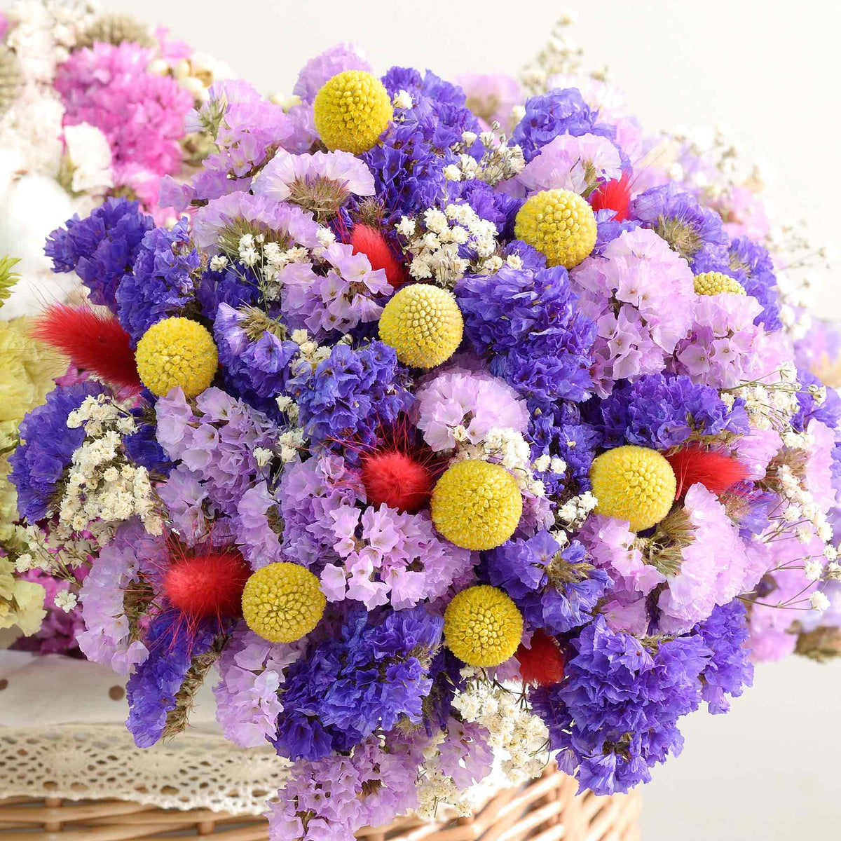 A close-up of vibrant yellow, purple and pink billy button flowers, showcasing its textured petals.