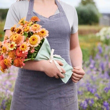 Person holding a bouquet of colorful flowers held together by boubqbags canvas bouquet sleeves in a natural setting
