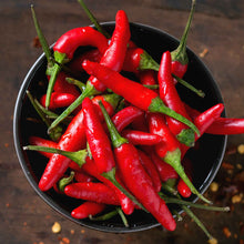 A cluster of small, vibrant Thai Super Chili F1 peppers with green stems, in a bowl.